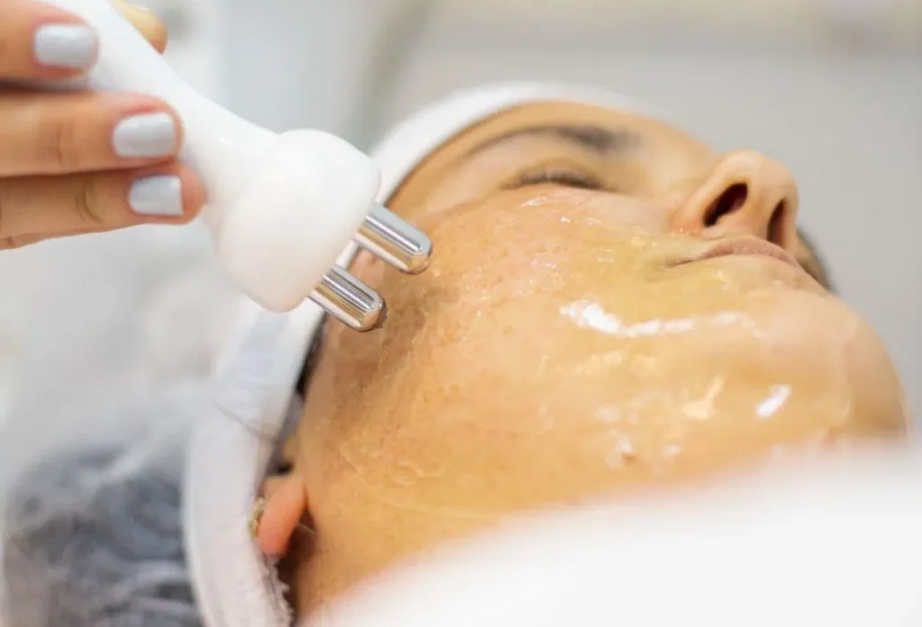 Mulher recebendo limpeza de pele profissional com máscara calmante em clínica de estética